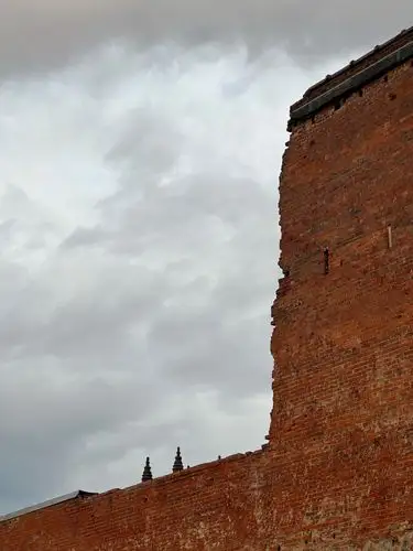 Ancient brickwork reaches up to a moody sky.